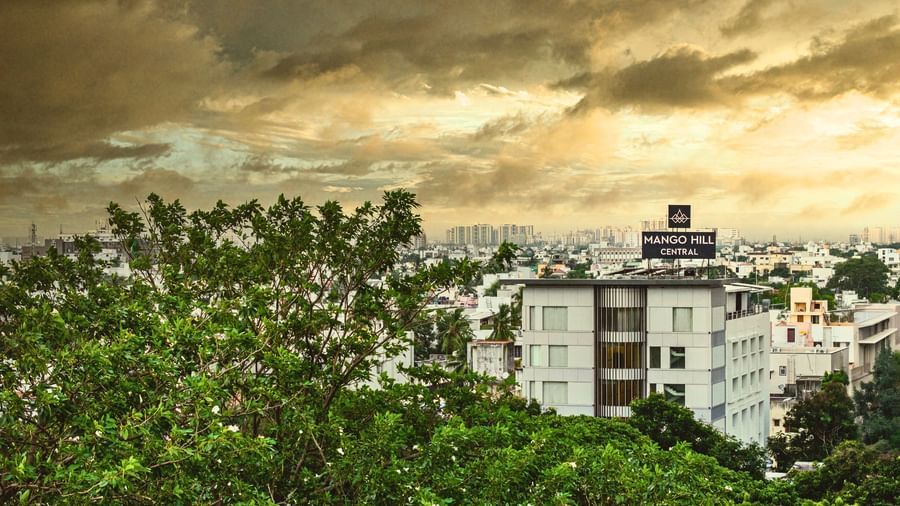 A view of the city of Chennai from a high vantage point, showing buildings and green trees under a cloudy sky.