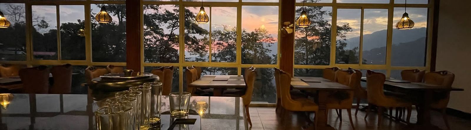 Overview of the Restaurant with seating arrangements and large windows with a view - Sumitel Gangtok