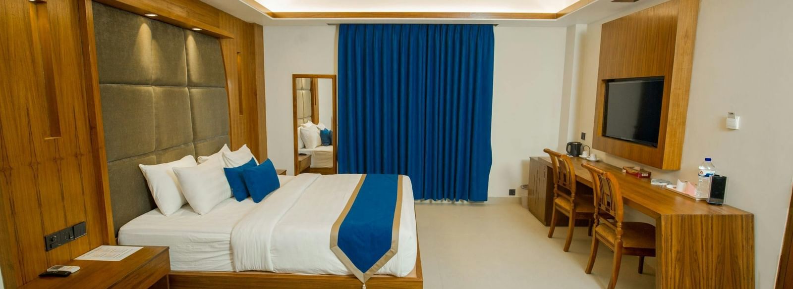 A spacious room featuring a large bed, a practical desk, a cosy seating area, and stylish modern decor