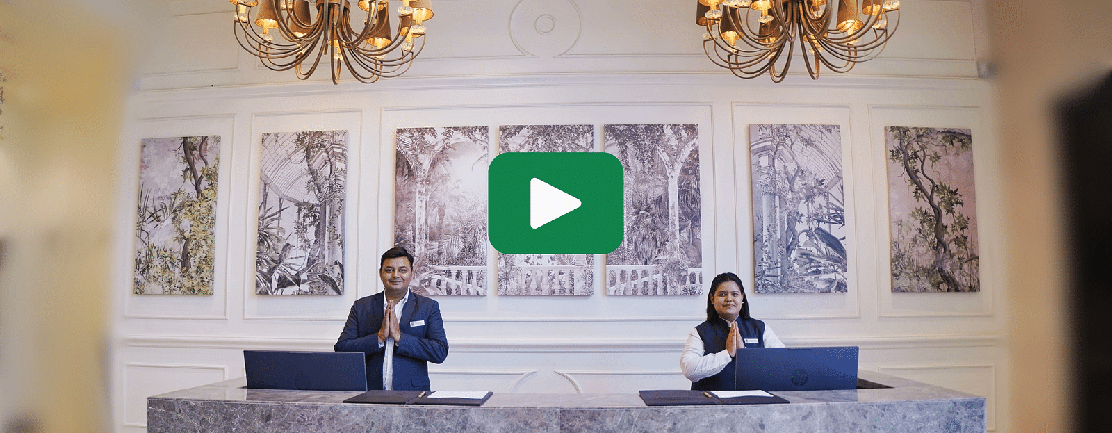 Two staff members standing behind the reception desk with a youtube logo in the centre - Rhythm Gurugram