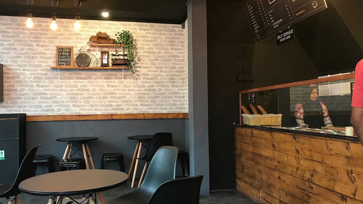 A cosy, dimly lit bar or cafe interior with exposed brick and industrial-style lighting.