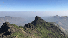 A far out view of Mount Girnar with other mountains in view that are covered by mist