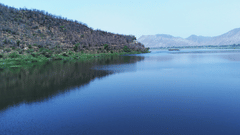An overview of Siliserh Lake with a hill on the left and mountains in the background