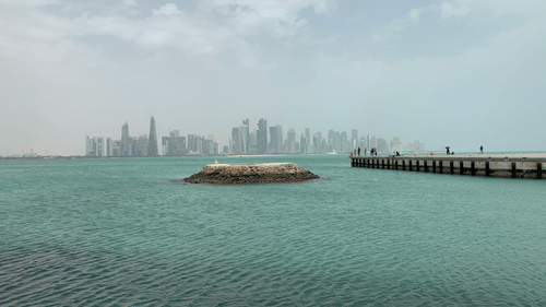 An island viewing the city of doha with people standing on a bridge