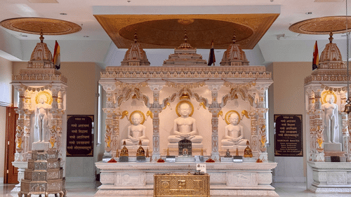White marble Jain temple interior featuring ornate shrines, carved pillars, glowing chandeliers, polished flooring, and a peaceful atmosphere for worshippers and visitors