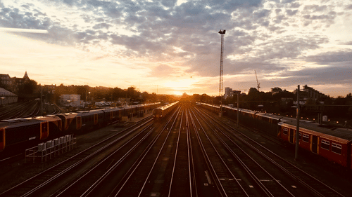 A landscape view of a trains passing along during sunrise.