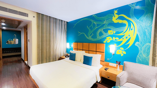 An image of a bedroom with king size bed, bedside table, a sofa, and centre table