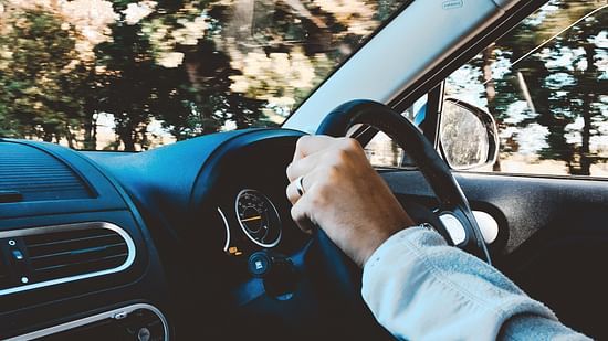 A persons Hands on a steering wheel 