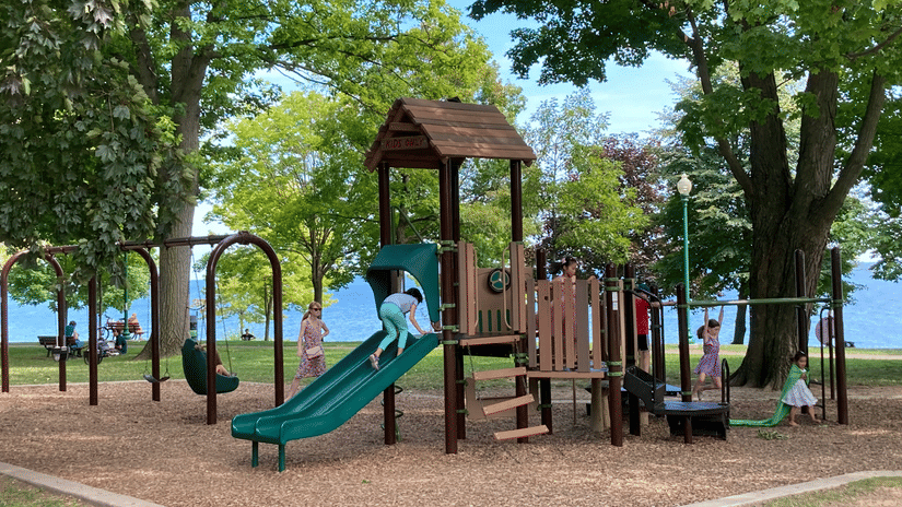 A view of a children's park with a slide as well as swings in view and a lake in the distance, highlighting Pookode Lake Activities.