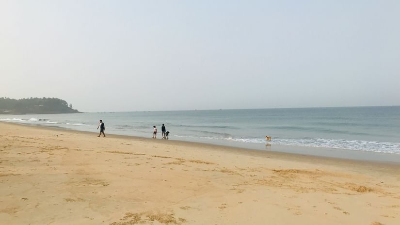An overview of one of the Beaches in Kochi with few people walking away from the shoneline.