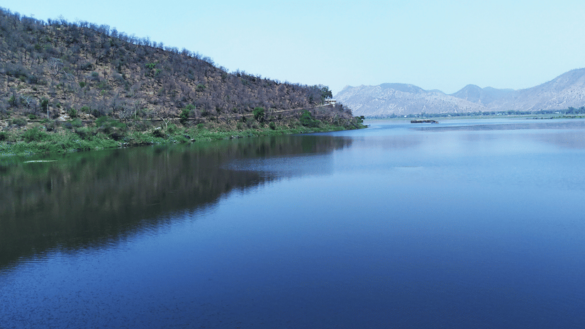 An overview of Siliserh Lake with a hill on the left and mountains in the background