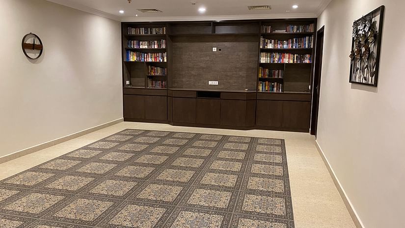 A room with a patterned carpet, built-in bookshelves, and a piece of artwork on the wall. - Still Waters, Varkala