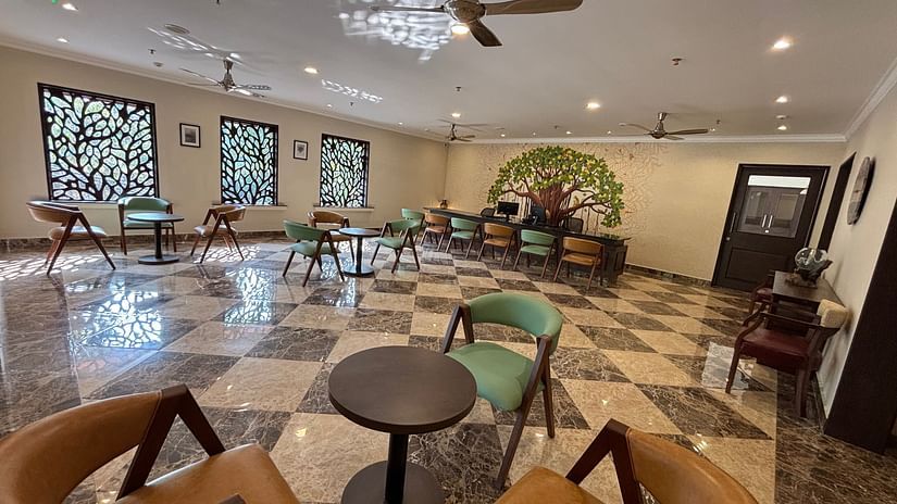 A cosy dining setting with chairs around tables with a wallpaper background at a restaurant. - Still Waters, Varkala