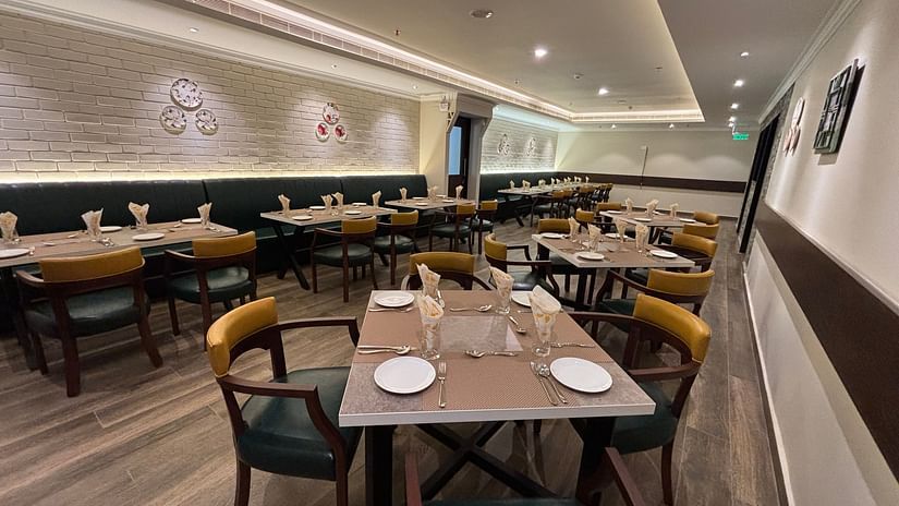 Dining seating at West Coast with white walls and minimal paintings and chairs surrounding tables. - Still Waters, Varkala