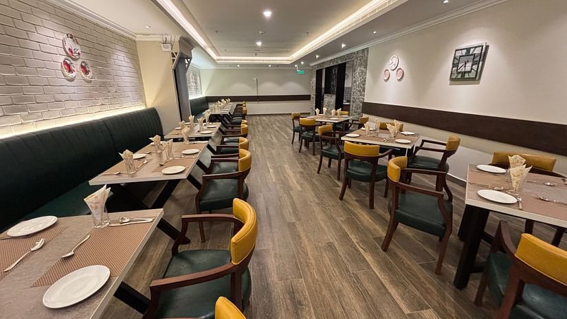 The interior of West Coast with tables set for dinners and a long sofa along the wall.