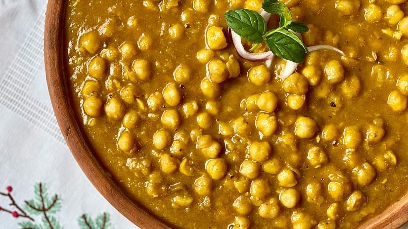 A bowl of chole garnished with onions