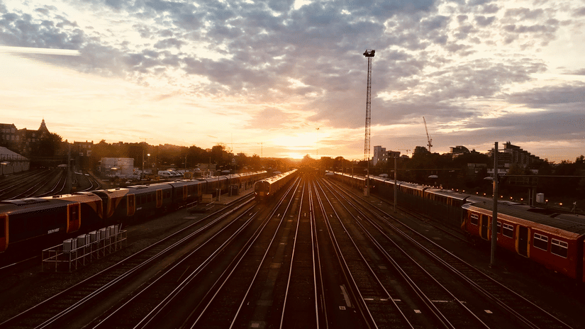 A landscape view of a trains passing along during sunrise.