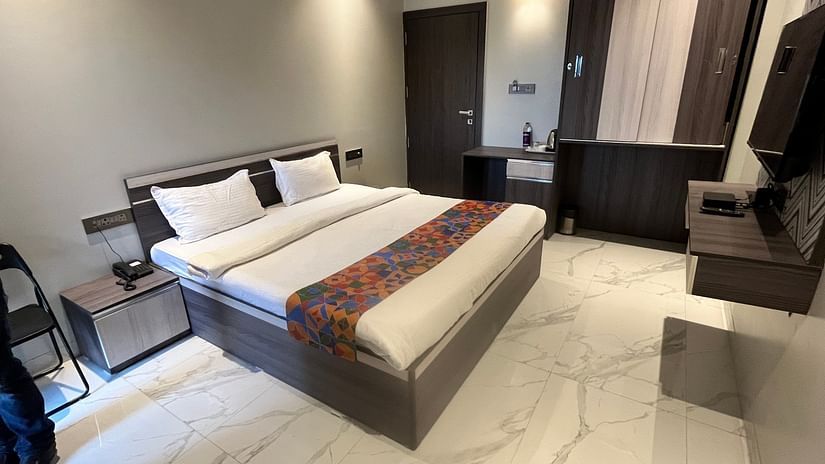A hotel bedroom with a large bed with a head board, a night stand, a television and a cup board to the side at VITS Select Kharadi, Pune.