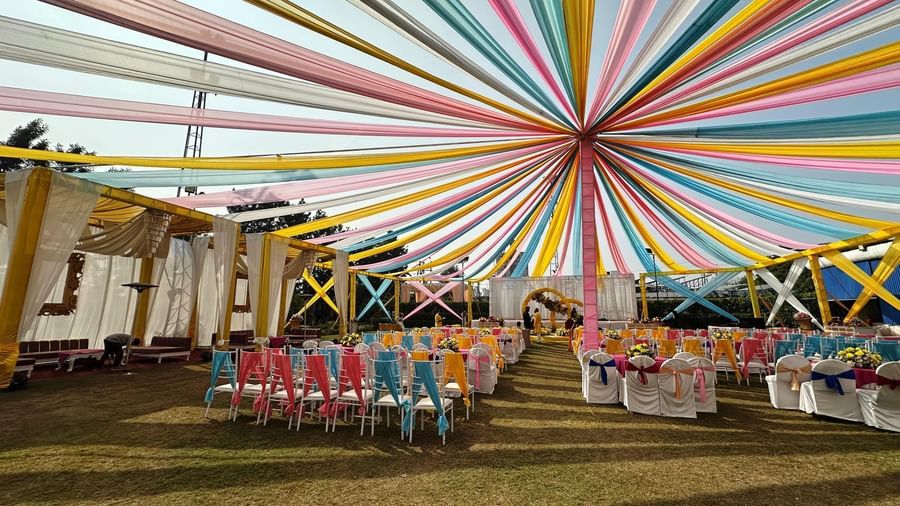Colorful outdoor wedding setup under a vibrant canopy at Amer Greens, with arranged seating and festive decor.