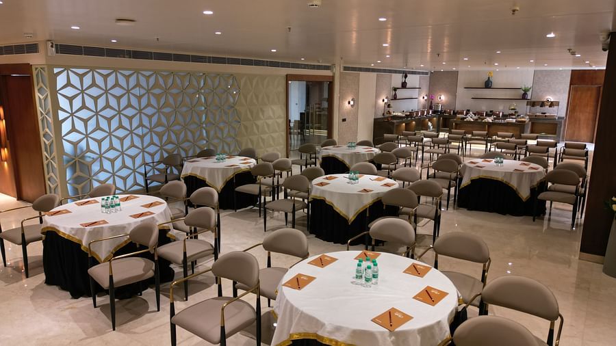 A well-arranged dining area with neatly set tables and chairs, each table covered with tablecloths at Clarks Collection Grand Sapphire, Ajmer.
