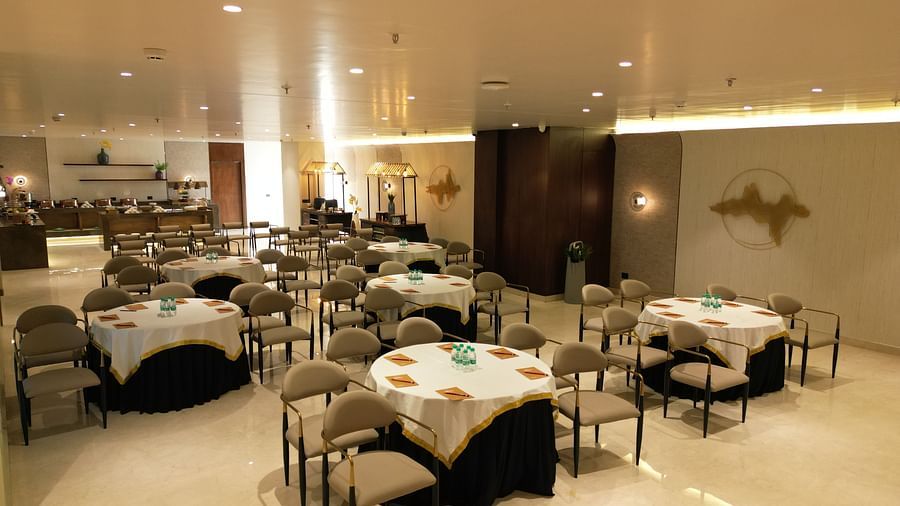 A well-lit dining area with neatly arranged tables, chairs, and cutlery placed on the tables at Clarks Collection Grand Sapphire, Ajmer.