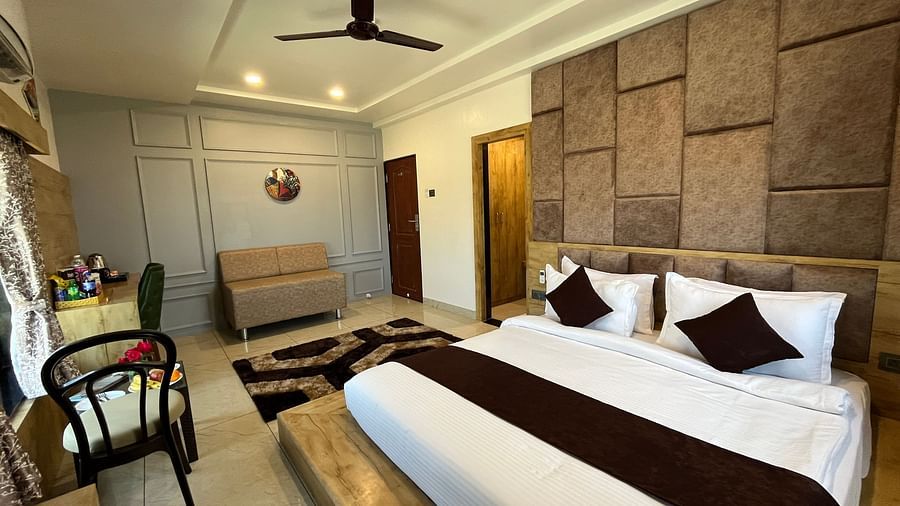 Side view of the premier room with a king-sized cosy bed and a sofa in the corner at Clarks Collection, Somnath