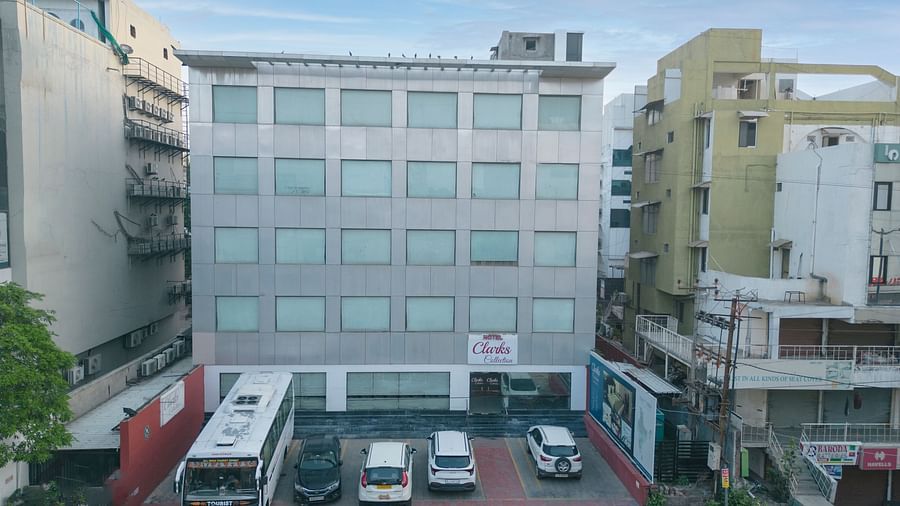 The view of Clarks Collection, Vadodara, with parked vehicles in front of the hotel building.
