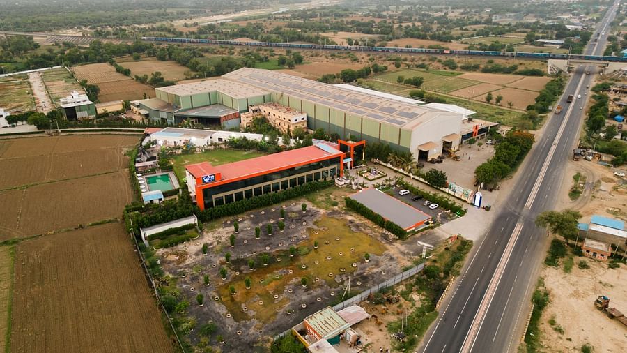 Theview of Clarks Safari Kheda, a large estate with multiple structures nestled among open land and a distant road, under vast sky.
