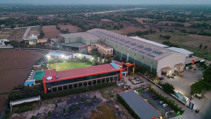Wide aerial view of Clarks Safari Kheda, revealing a collection of buildings, a significant open space, and surrounding natural terrain.