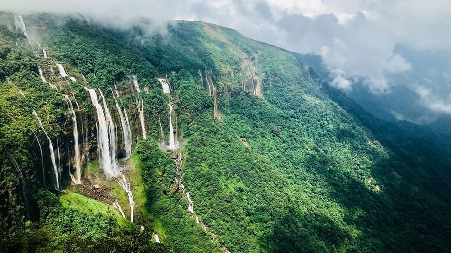 A green hill overlooks the clouds