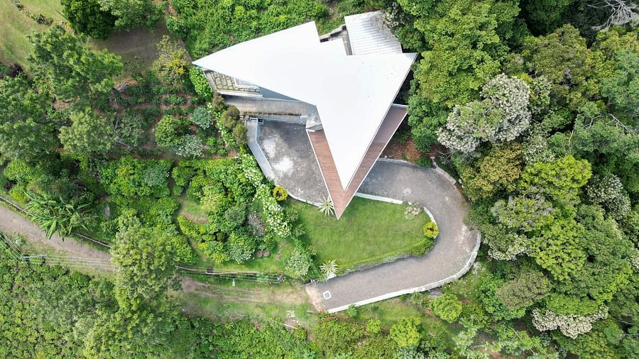 Aerial view of a modern hillside villa surrounded by dense green forest at Ibex Resorts, Coonoor (Tapas).