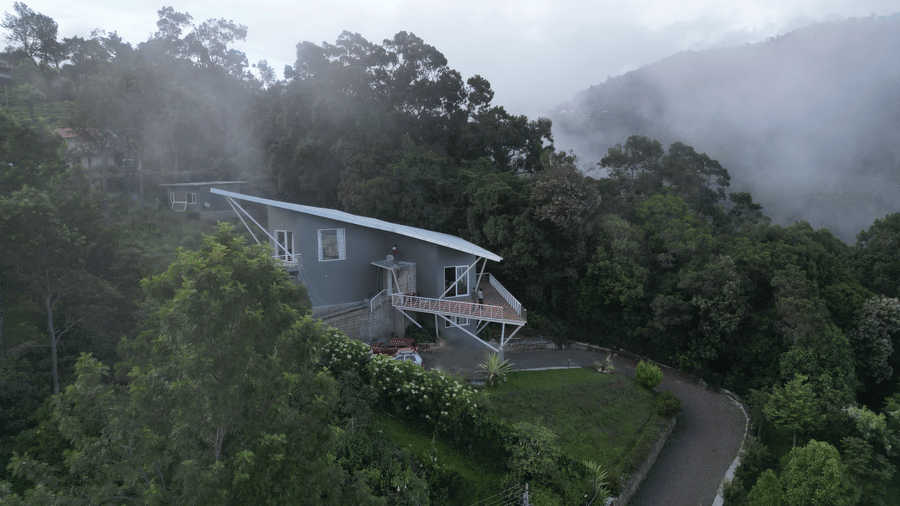 Angled view of a modern house overlooking a scenic coastal landscape with greenery Ibex Resorts, Coonoor (Tapas).