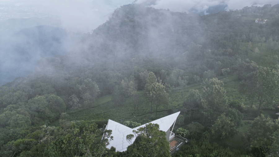 Home on a winding road through misty hills with forest and mountains in the background at Ibex Resorts, Coonoor (Tapas).