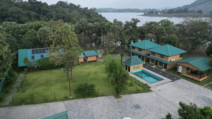 Wide aerial shot showing the resort layout including the swimming pool, guest cottages, and surrounding forest - Ibex Resorts, Malampuzha (Kava Eco Camp and Caravan Park)