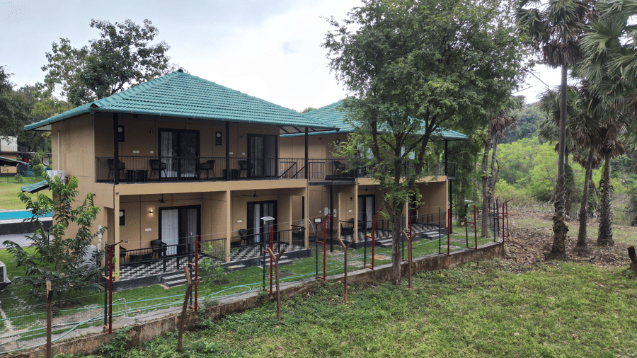 2-storey resort building with private balconies surrounded by a lush natural landscape and tall trees - Ibex Resorts, Malampuzha (Kava Eco Camp and Caravan Park)