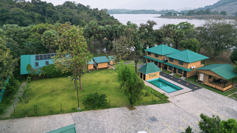 The facade of Ibex Resorts, Malampuzha (Kava Eco Camp and Caravan Park), featuring trees, and greenery in the morning.