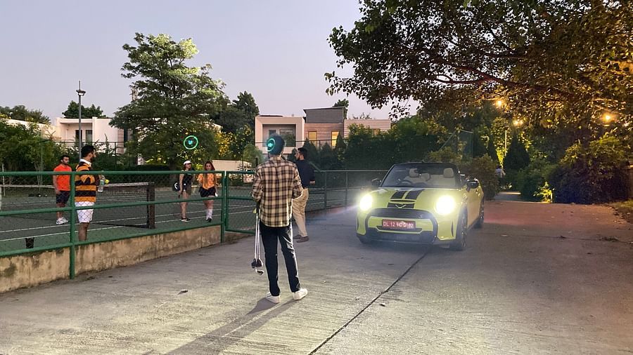 A person standing in front of a car on a stone pathway - Karma Lakelands.