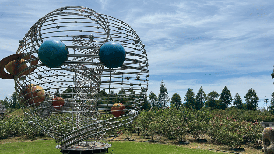 Science-inspired metal sculpture displayed in a landscaped garden.