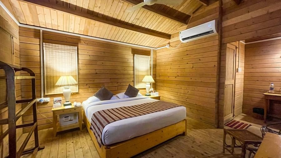  A warm and inviting wooden cabin interior with a comfortable bed, elegant furnishings, and modern amenities, all under a cosy vaulted ceiling- Lotus Eco Beach Resort Konark