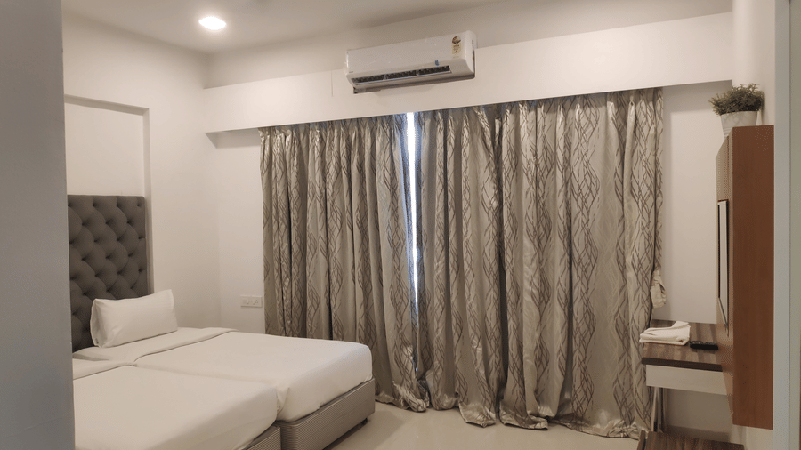 A view of a bedroom that has a ceiling fan, AC and twin beds in a 2 BHK service apartment in Chandivali, Mumbai
