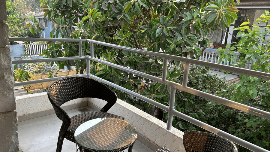 A serene private balcony with stylish wicker chairs and a glass-top table, surrounded by lush greenery– Maxxvalue Klub Klass Villa, Lonavala.