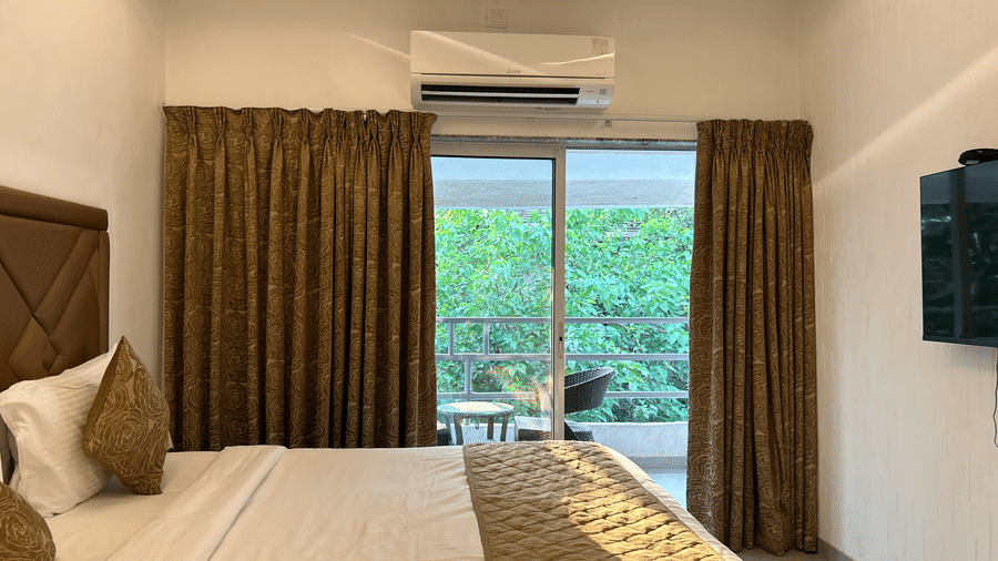 A bedroom with a balcony, featuring warm lighting, an air-conditioner, and a scenic view – Maxxvalue Klub Klass Villa, Lonavala.