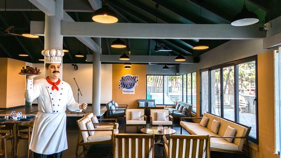 Statue of a chef standing inside Song of the Sea restaurant near the seating area.