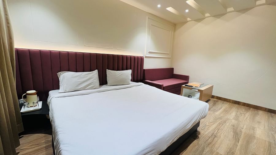Premium rooms with pleasant white ceiling lights and a bedside table with wooden ply flooring- Hotel Morya, Bhopal