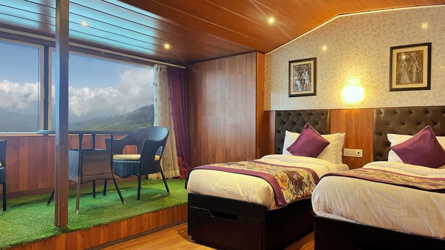 Attic Room at Mount Amara Hotel & Spa featuring twin beds, bedside table, lamps, wooden ceiling with lights, and a balconyattached.