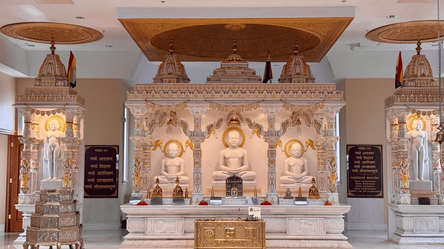 White marble Jain temple interior featuring ornate shrines, carved pillars, glowing chandeliers, polished flooring, and a peaceful atmosphere for worshippers and visitors