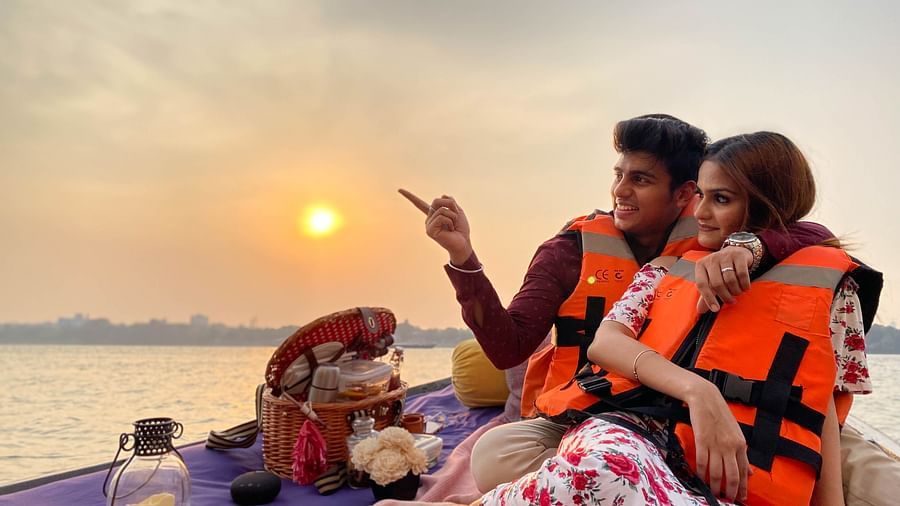 a couplle having a picnic on a boat wearing life vests and the sun setting in the background - Polo Floated Kolkata