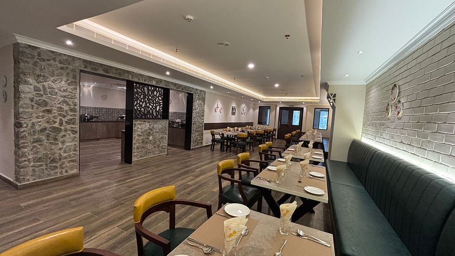 The interior of a restaurant with tables set for dinners and a long bench seat along one wall.