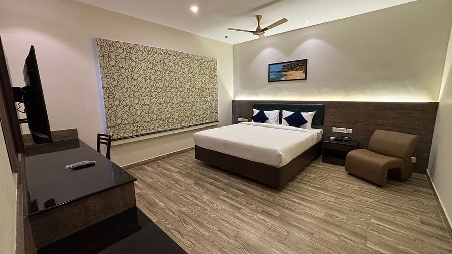 A king size bed in a Family Suite with an armchair in the corner. - Still Waters, Varkala