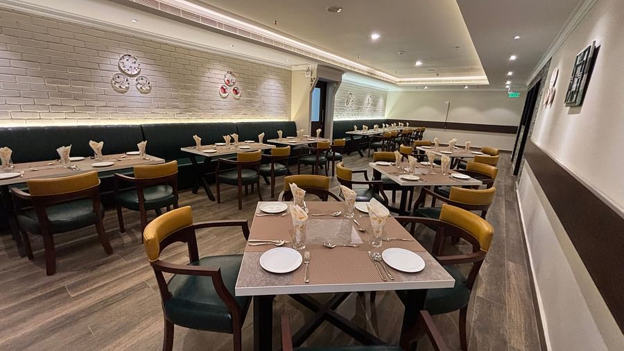 Dining seating at West Coast with white walls and minimal paintings and chairs surrounding tables. - Still Waters, Varkala